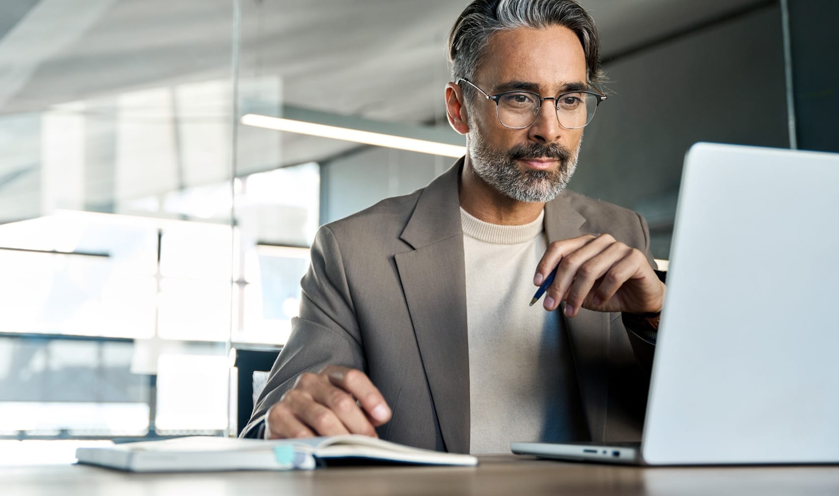 Image - Mature busy businessman executive looking at laptop sitting at desk. Copy space.